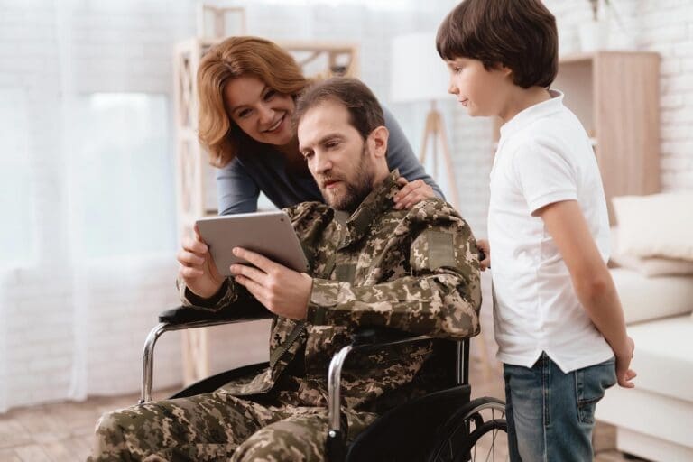 Featured image for 100% VA Disability Benefits, showing a disabled Veteran in a wheelchair with his family